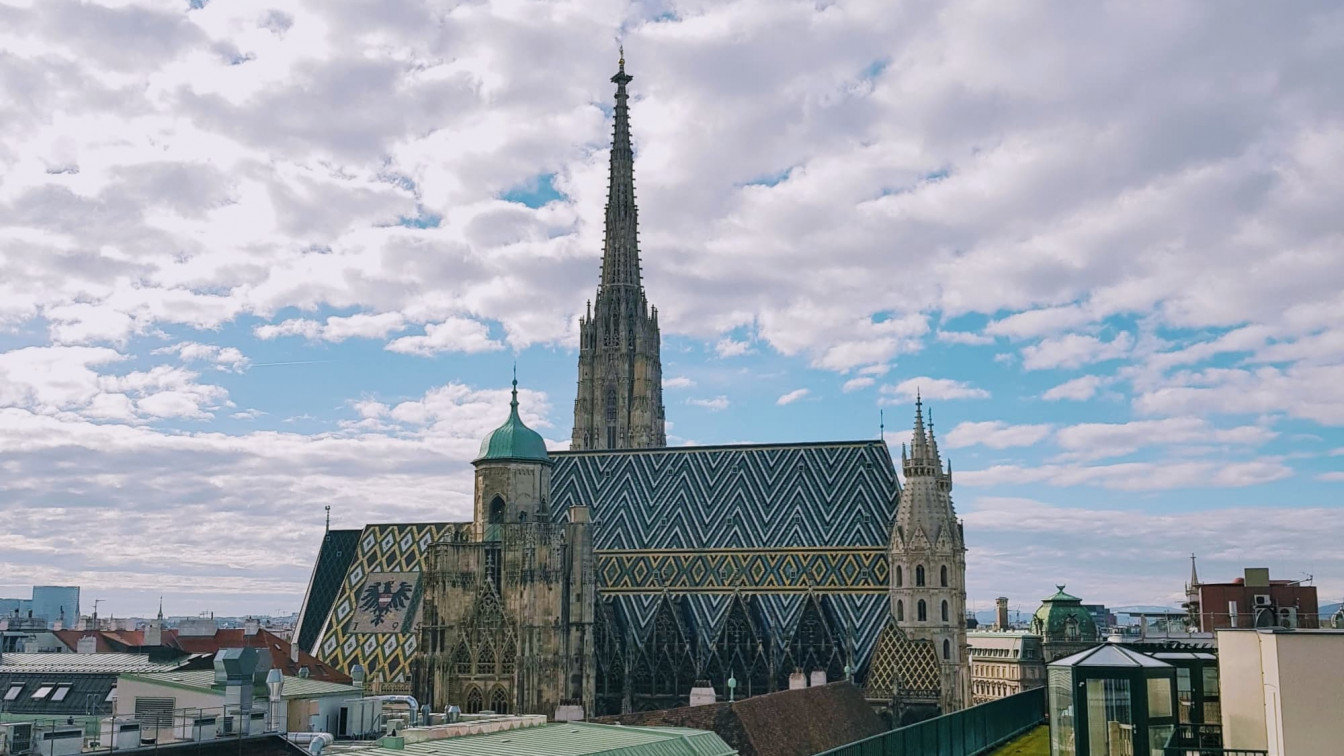 Beitragsbild: Ansicht des Wiener Stephansdom im 1. Bezirk vor blauem Himmel mit Schäfchenwolken von einer Dachterrasse aus.