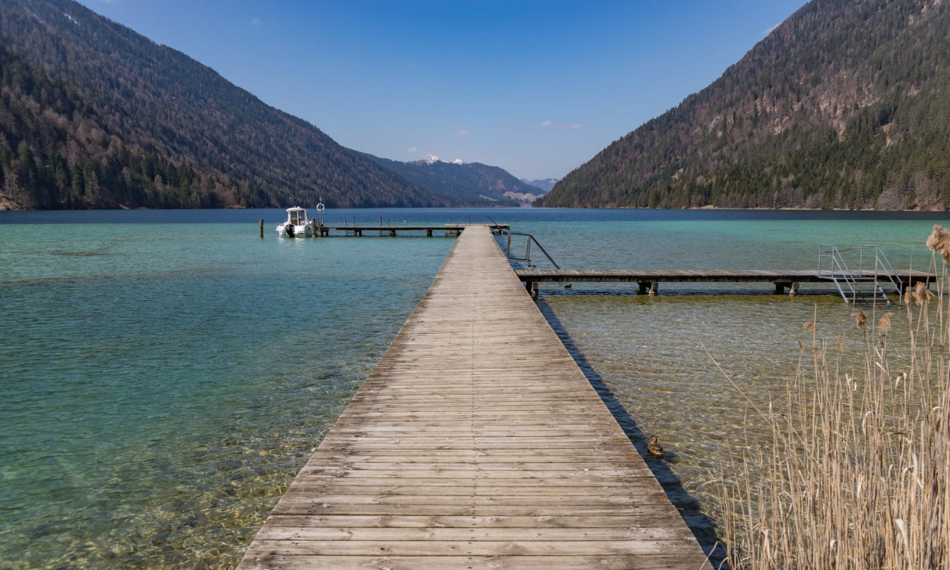 Ein Steg, der ins türkisblaue Wasser eines Sees in Kärnten führt