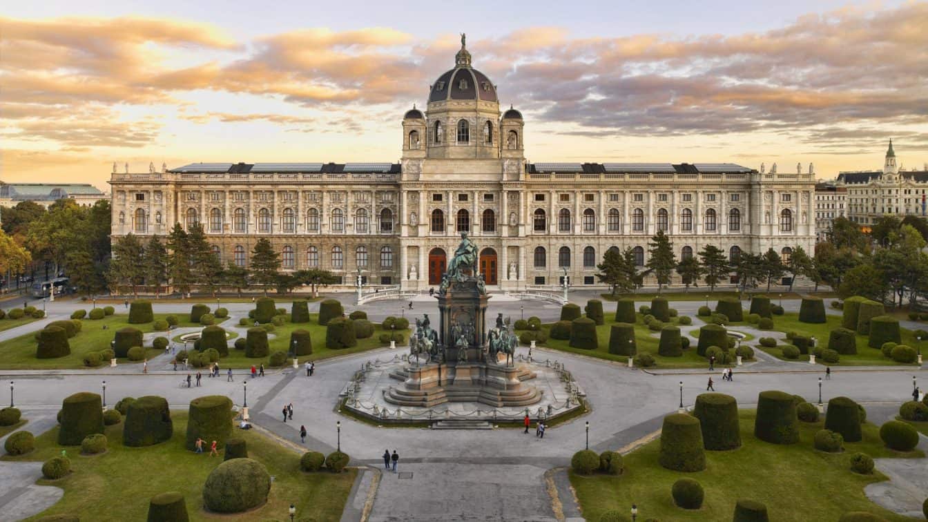 Ein Bild vom Kunsthistorischen Museum in Wien, davor ist der Vorplatz zwischen den Museen zu erkennen, dahinter der Sonnenuntergang