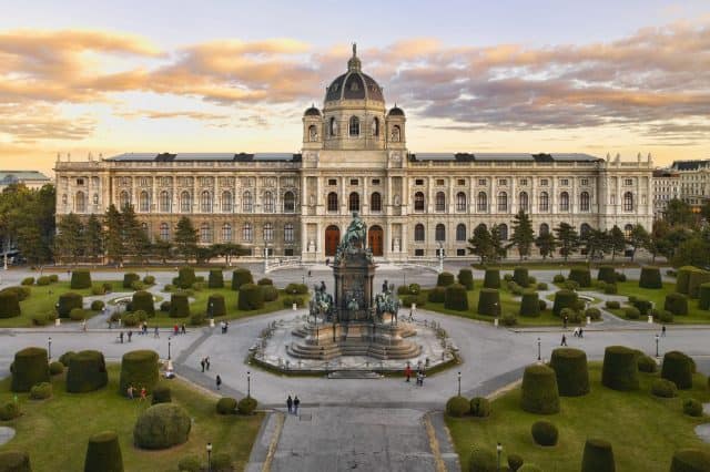Ein Bild vom Kunsthistorischen Museum in Wien, davor ist der Vorplatz zwischen den Museen zu erkennen, dahinter der Sonnenuntergang