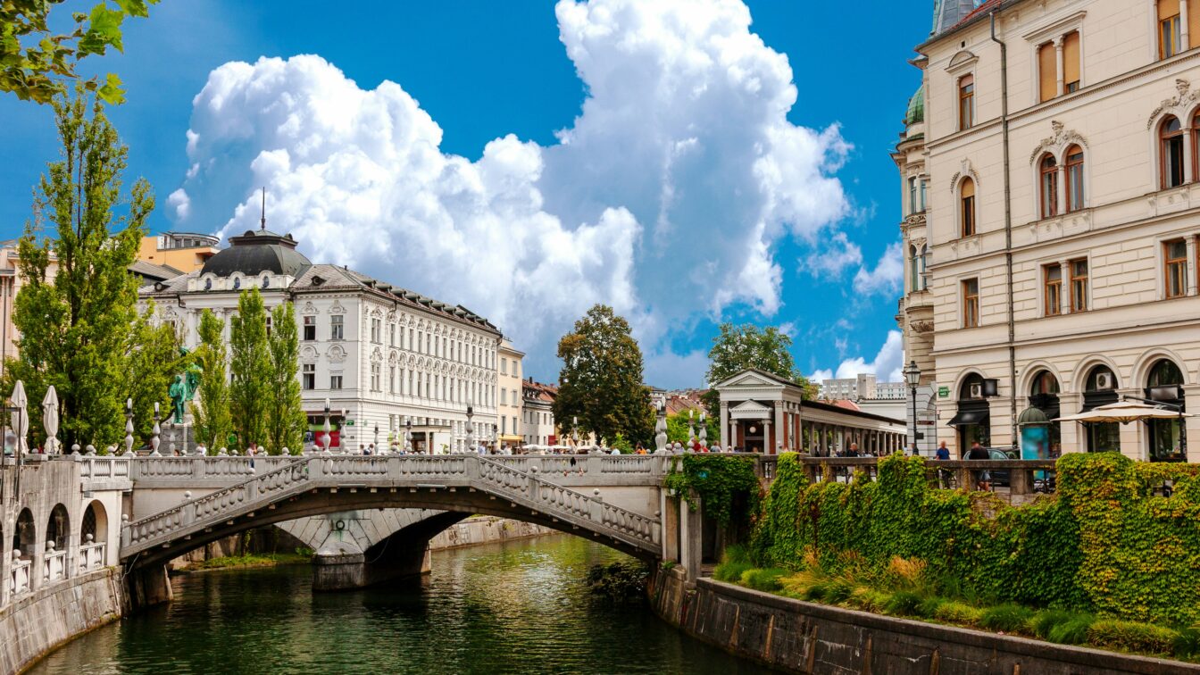 Stadtansicht von Ljubljana, Gebäude neben einem Fluss, große weiße Wolke