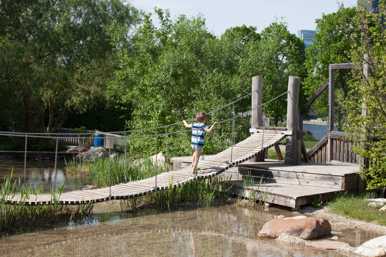 Ein Kind geht über eine Hängebrücke auf dem Wasserspielplatz auf der Donauinsel