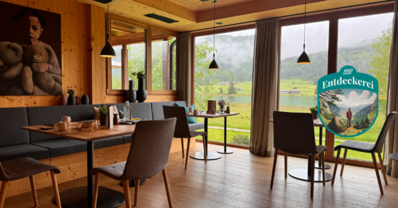 Genießerhotel die Forelle am Weissensee Gastraum mit Blick auf den See mit Entdeckerei Wappen