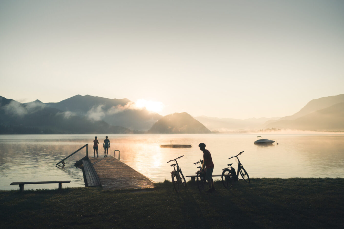 Radler im Sonnenuntergang am Steg des Gemeindebades Gschwendt in Strobl am Wolfgangsee im Salzkammergut
