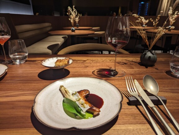 Jola Restaurant Wien: Ein Glas mit Rotwein und veganes fine dining Gericht