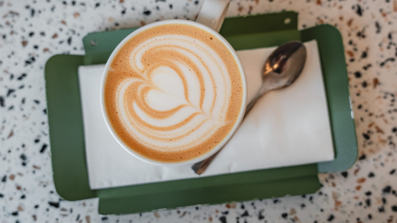 Cappuccino mit Latte Art auf grünem Tablett