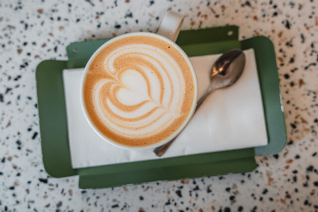 Cappuccino mit Latte Art auf grünem Tablett