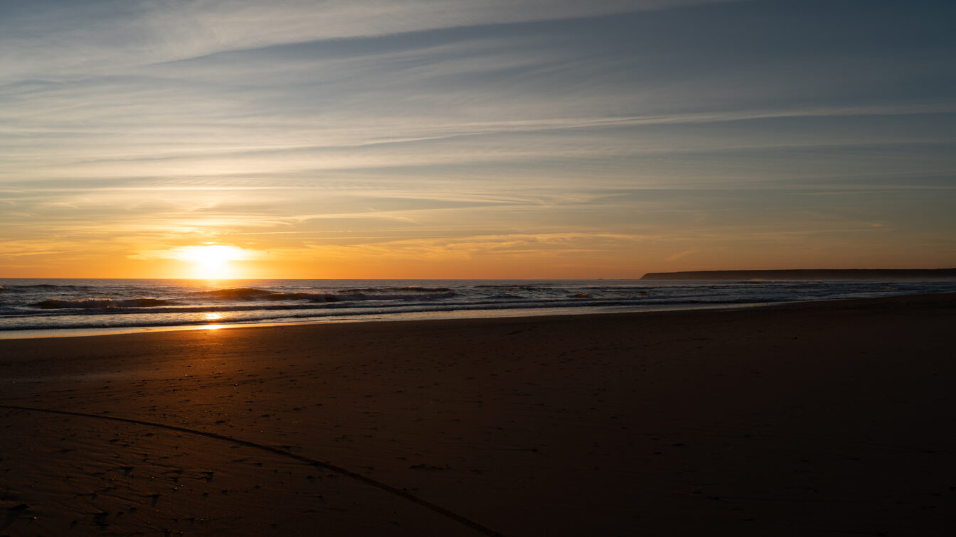 Sonnenuntergang am Meer mit sanften Wellen und leerem Sandstrand – stimmungsvolle Abendstimmung an der Küste, perfekt für romantische Strandspaziergänge und Naturfotografie.