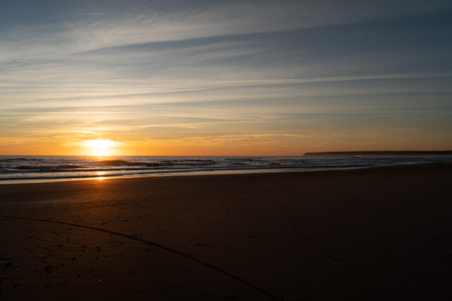 Sonnenuntergang am Meer mit sanften Wellen und leerem Sandstrand – stimmungsvolle Abendstimmung an der Küste, perfekt für romantische Strandspaziergänge und Naturfotografie.