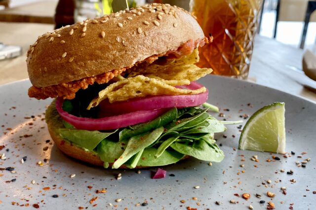 Veganer Burger mit Nachos und Babyspinat auf einem Teller