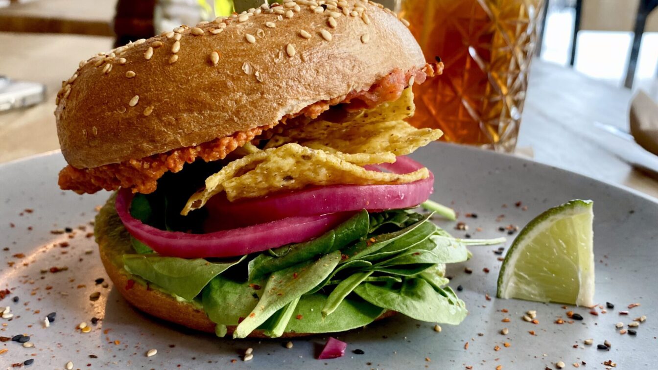 Veganer Burger mit Nachos und Babyspinat auf einem Teller