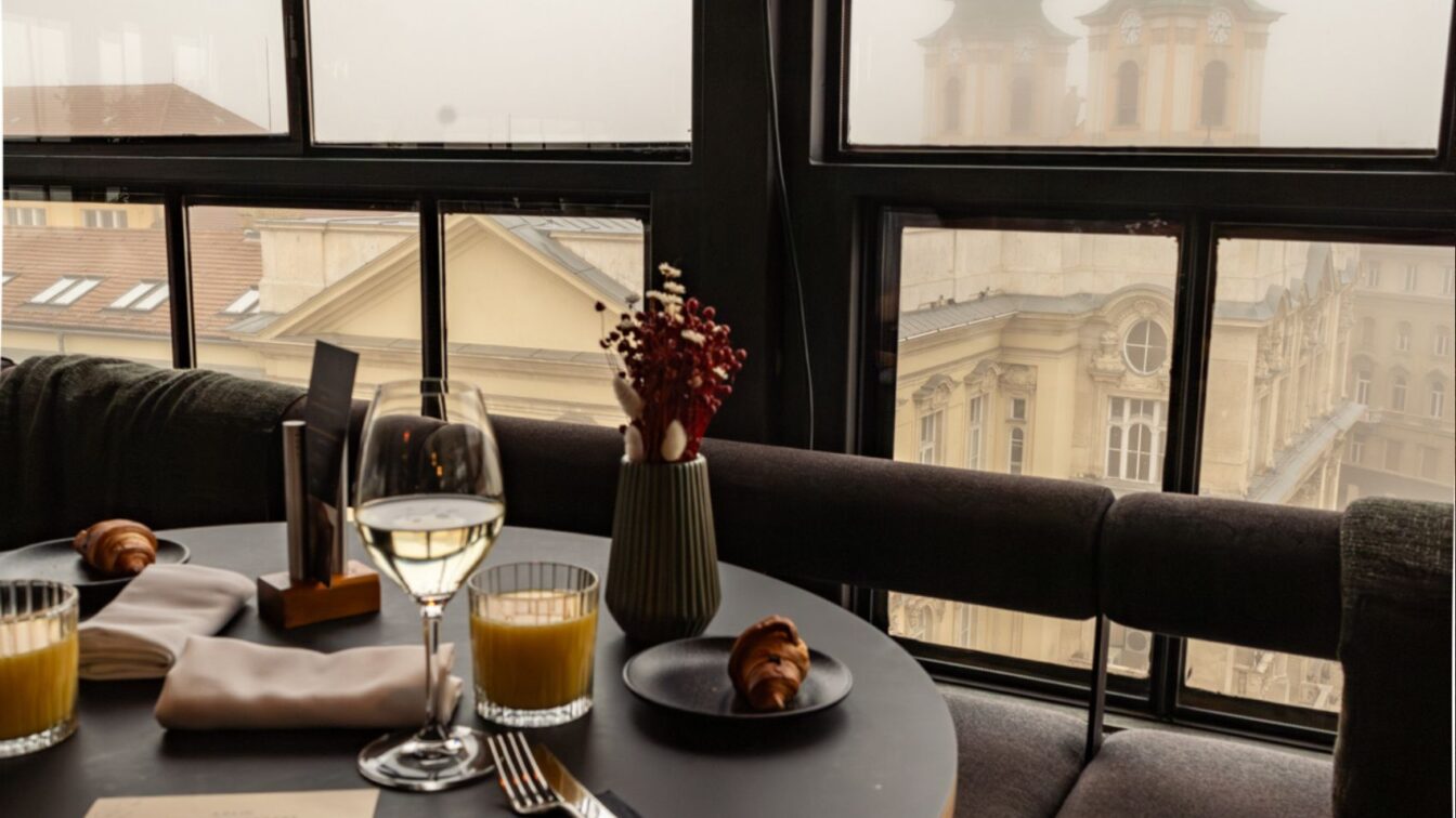 Stilvoll gedeckter Frühstückstisch in einem der besten Hotels Budapests mit Blick auf historische Fassaden und nebelverhangene Kirchtürme – elegantes Ambiente über den Dächern der Stadt