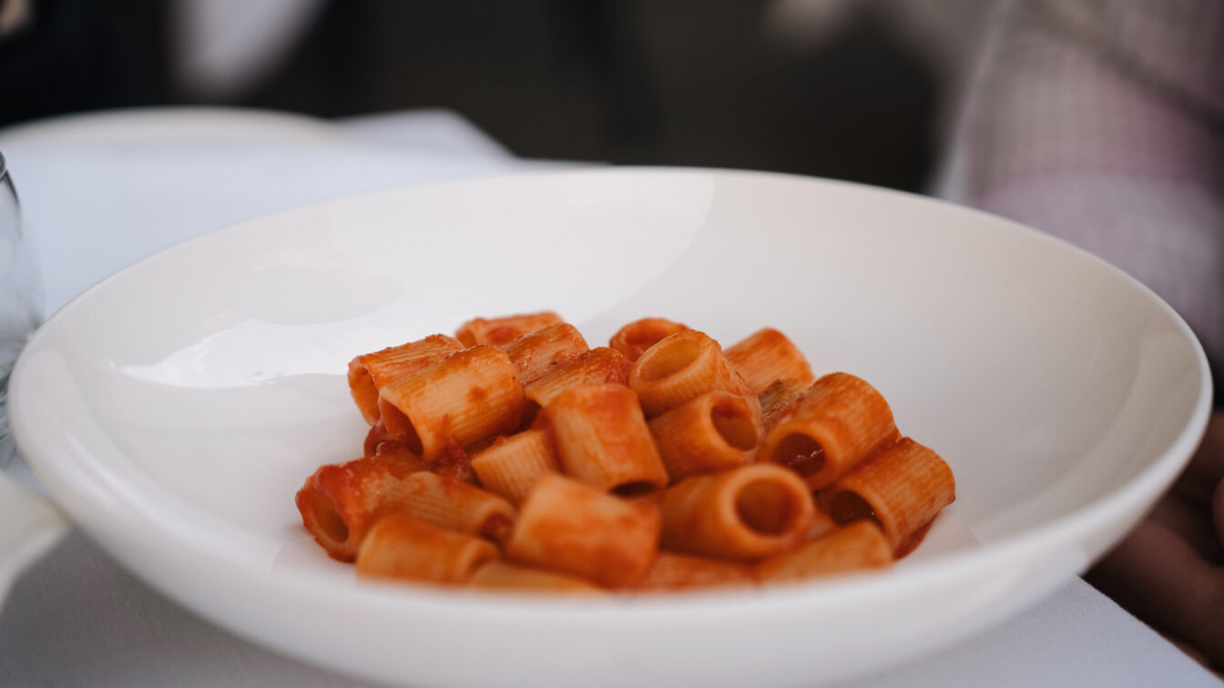 Teller mit klassischer italienischer Rigatoni Pasta in fruchtiger Tomatensauce, serviert im eleganten Ambiente von Harry’s Bistrò
