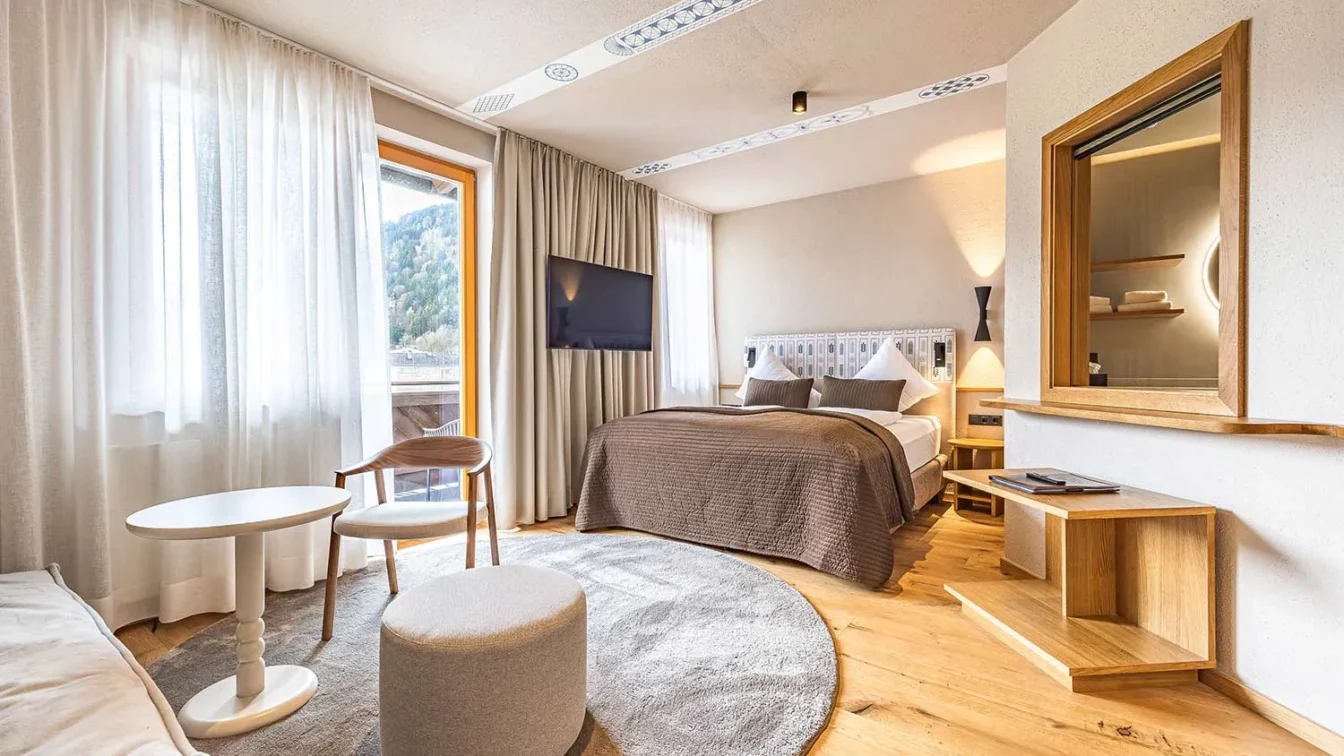 Ein helles Hotelzimmer mit Sofa, Bett und cremefarbenen Möbel.