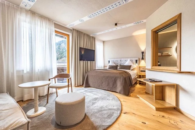 Ein helles Hotelzimmer mit Sofa, Bett und cremefarbenen Möbel.