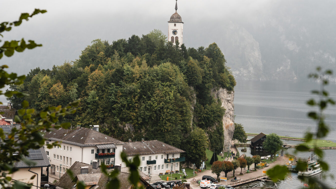 Eine Kirche auf einem Hügel in herbstlicher Ortschaft am See