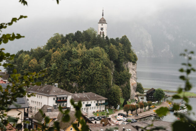 Eine Kirche auf einem Hügel in herbstlicher Ortschaft am See