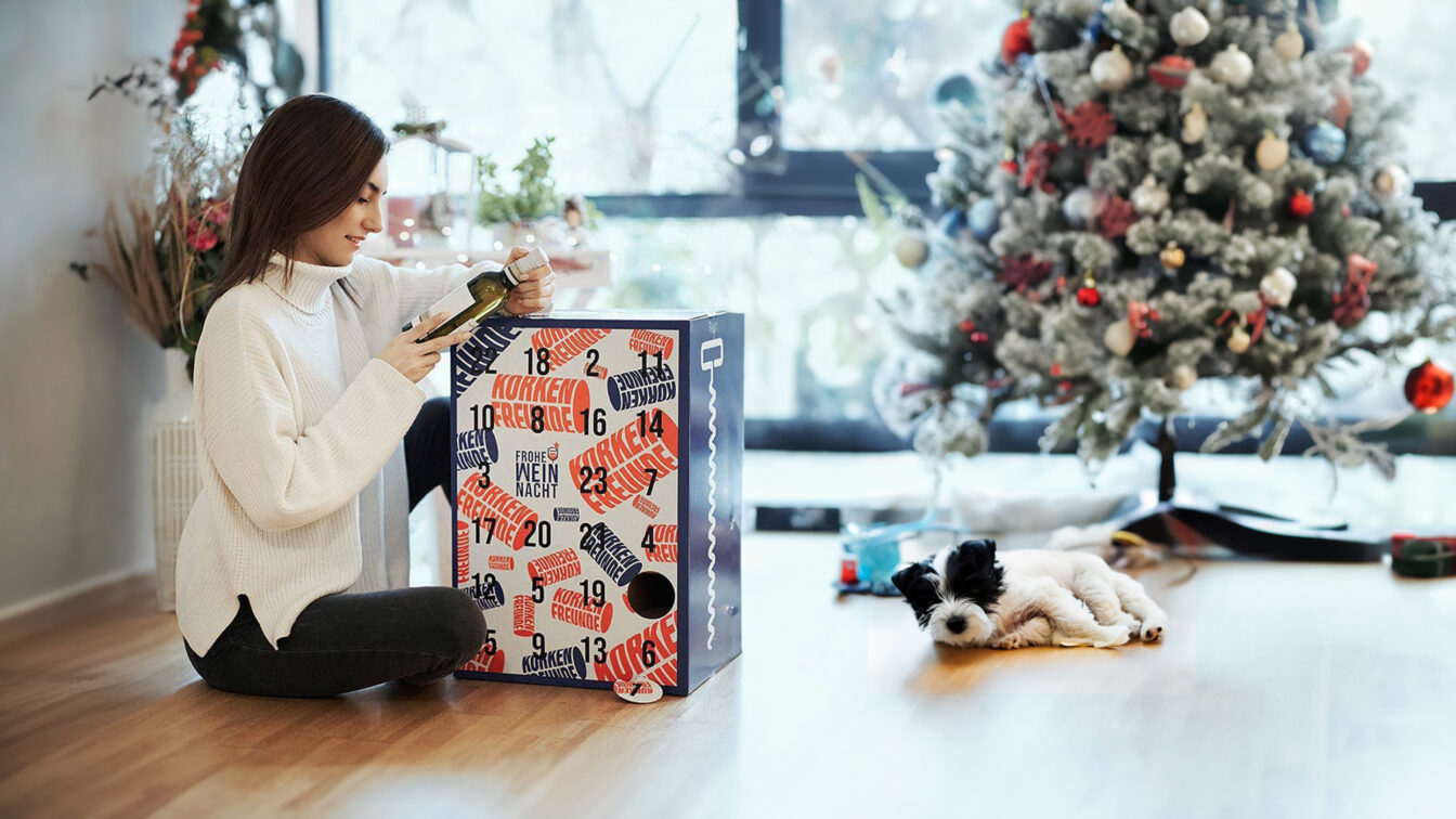 Korkenfreunde: Alkohol-Adventkalender mit Wein, Frau mit Hund packt ihn aus
