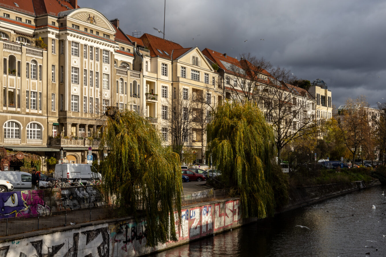 Uferpromenade am Landwehrkanal in Berlin-Kreuzberg mit historischen Altbauten, Weidenbäumen und Graffiti – beliebte Fotolocation und Spazierweg im Kreuzberg Guide.