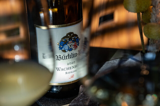 Nahaufnahme einer edlen Weinflasche vom Weingut Bürklin-Wolf, Jahrgang 2020, Wachenheimer Riesling, in stilvoller Atmosphäre mit gedämpftem Licht und eleganten Gläsern – typische Szene in einer gehobenen Weinbar in Berlin, ideal für Genießer und Weinliebhaber.