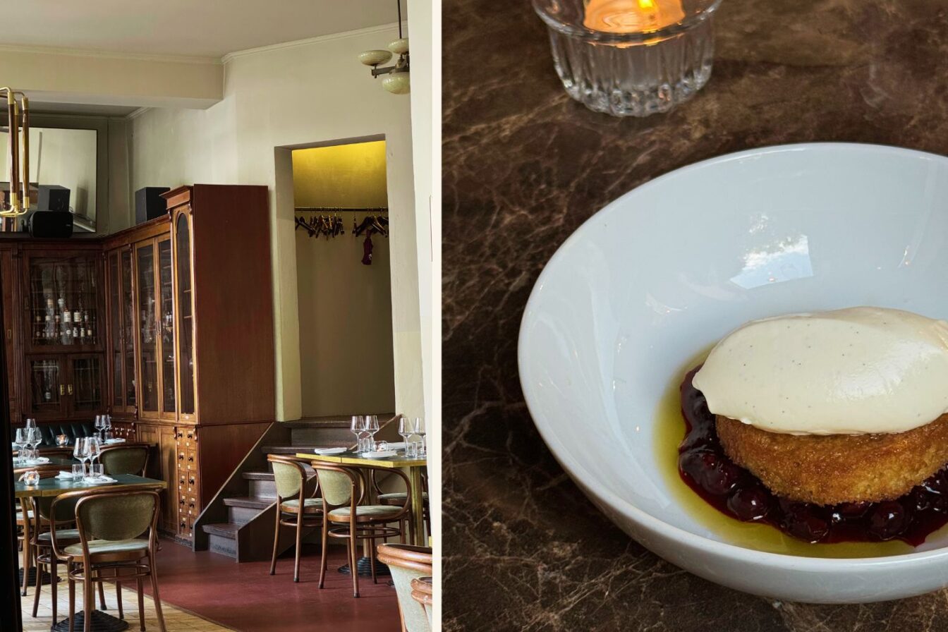 Innenansicht des Restaurants ORA in Berlin mit eleganten Holzmöbeln, grünen Stühlen und gedeckten Tischen, links im Bild ein antiker Apothekerschrank, im rechten Bildteil ein Dessert in einer weißen Schale mit goldbraunem Kuchen, dunkler Beerensauce, einem Klecks heller Creme und einem kleinen Kerzenlicht im Hintergrund.