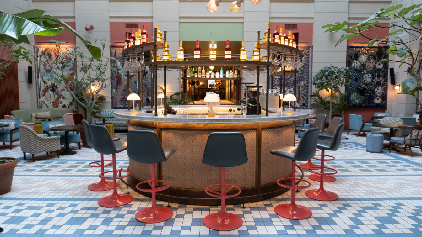 Eine bunte Halle mit schönen Designelementen und einer runden Bar in der Mitte eines Hoteleingangs in Kopenhagen.