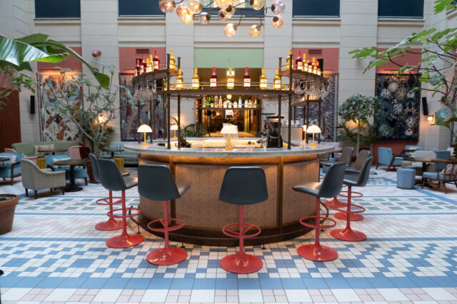 Eine bunte Halle mit schönen Designelementen und einer runden Bar in der Mitte eines Hoteleingangs in Kopenhagen.