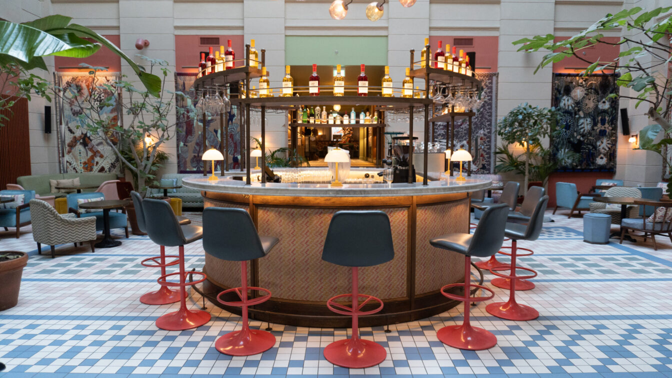 Eine bunte Halle mit schönen Designelementen und einer runden Bar in der Mitte eines Hoteleingangs in Kopenhagen.