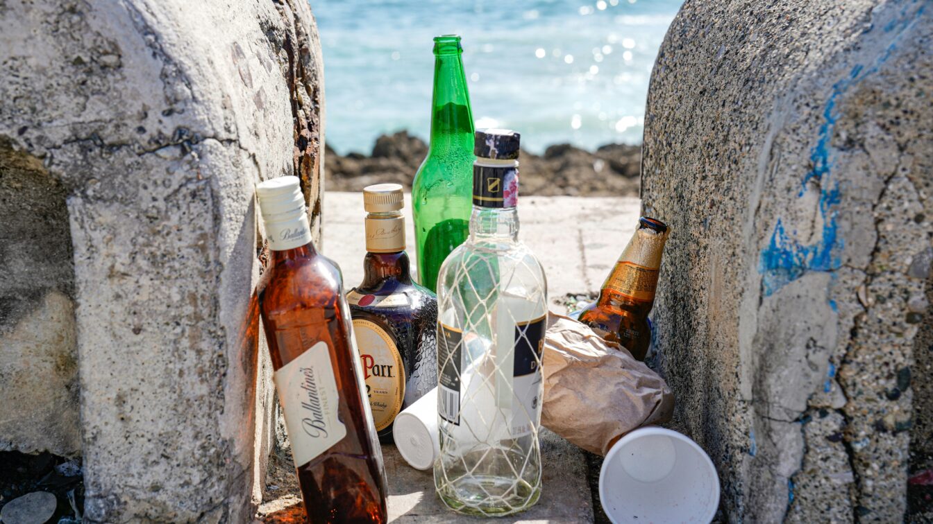 leere Flaschen alkoholischer Getränke stehen am Strand herum