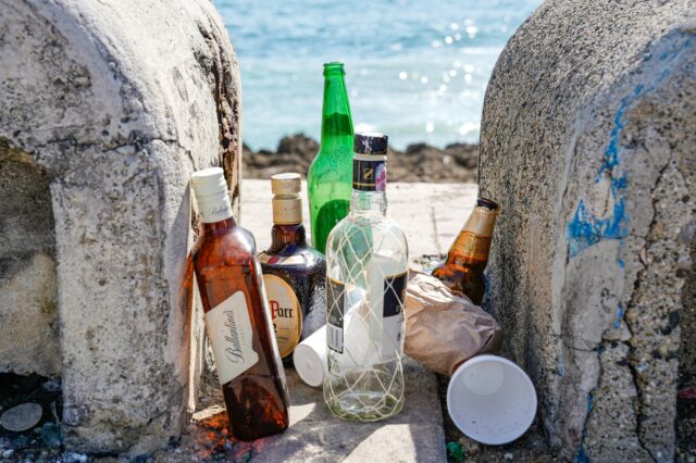 leere Flaschen alkoholischer Getränke stehen am Strand herum
