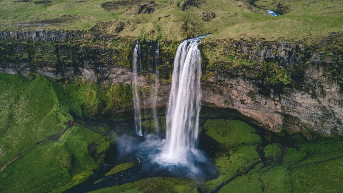 Grüne Wiesen in Island mit Wasserfall