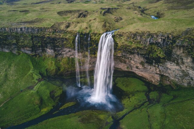 Grüne Wiesen in Island mit Wasserfall