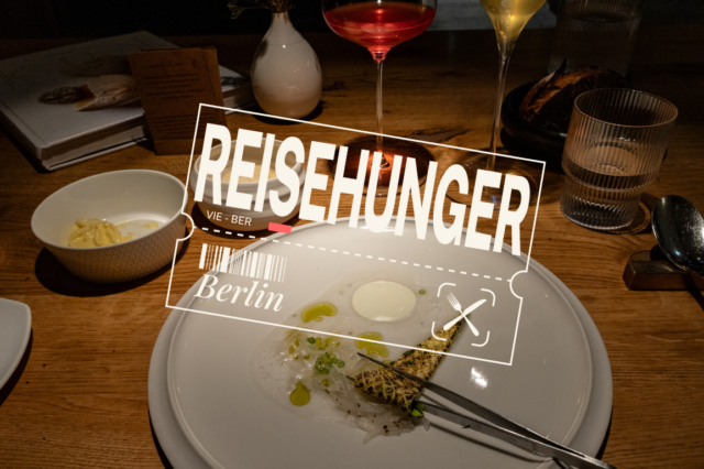 Dieses Bild zeigt eine fein gedeckte Restaurant-Tafel im Restaurant Horváth in Kreuzberg, Berlin. Im Vordergrund befindet sich ein elegantes Gericht auf einem weißen Teller – dünn geschnittene Fischscheiben mit grünen Öltropfen, einer Sauce und einem gegrillten Stück Gemüse oder Brot. Ein Messer und eine Gabel liegen auf dem Teller. Links daneben steht eine Schale mit einer gelben Creme oder Butter. Im Hintergrund sind ein Brotteller, Gläser mit Wasser, Weiß- und Rotwein, sowie ein Buch mit einer Speisekarte zu sehen. Der Holztisch verleiht der Szene eine gemütliche Atmosphäre. Eine digitale Grafik mit dem Schriftzug „REISEHUNGER“ sowie „Berlin“ und einer stilisierten Bordkarte überlagert das Bild, was auf eine kulinarische Reise hinweist.