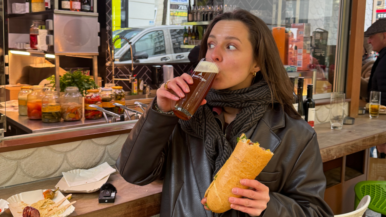 Frau mit Bier und Hot Dog beim Wiener Würstelstand