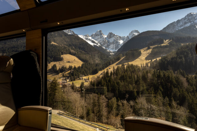 Blick aus dem GoldenPass Express auf grüne Täler und schneebedeckte Gipfel der Schweizer Alpen