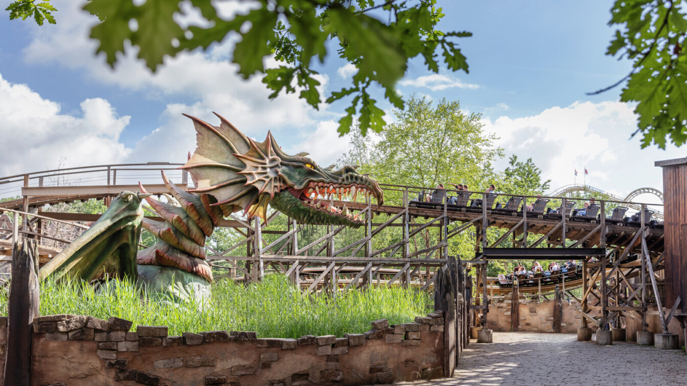 Ein Drachenkopf mit Achterbahn im Hintergrund im Efteling Freizeitpark.