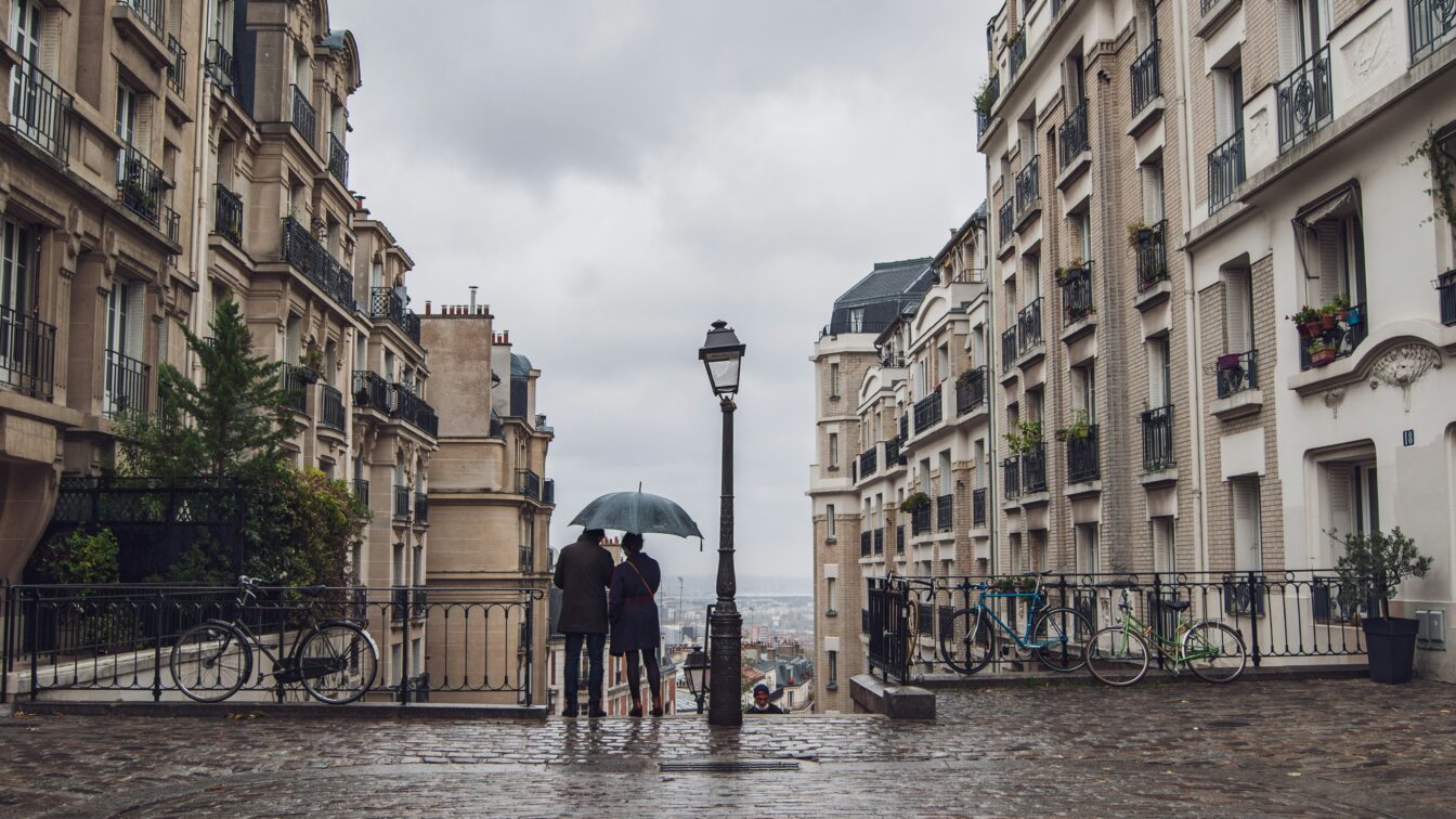 Regen in Paris, ein Paar unterm Regenschirm von Hinten.