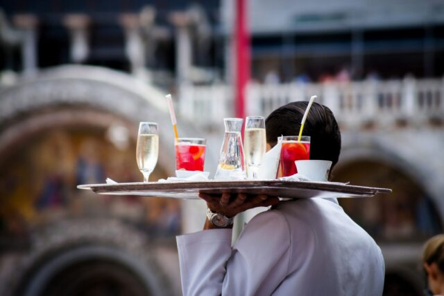 ein Kellner trägt ein mit Drinks beladenes Tablett