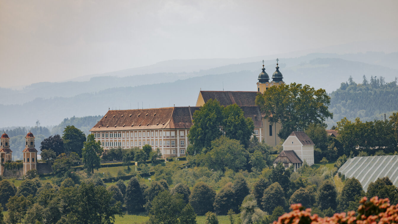 Historisches Kloster Stainz im Schilcherland in der Steiermark, eingebettet in grüne Hügel und Weinberge mit Blick auf die malerische Landschaft der Südweststeiermark.