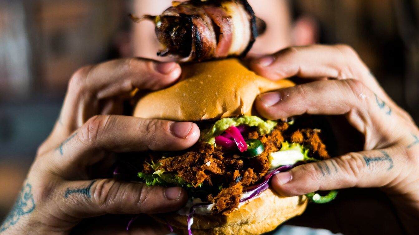 Ein Mann hält einen Burger in die Kamera