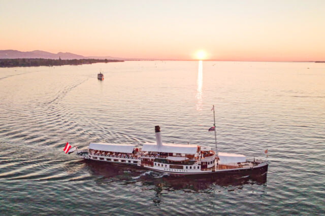 istorischer Schaufelraddampfer Hohentwiel auf dem Bodensee bei Sonnenuntergang – stimmungsvolle Schifffahrt vor der Kulisse von Bregenz und den Alpen, beliebte Attraktion in Vorarlberg.