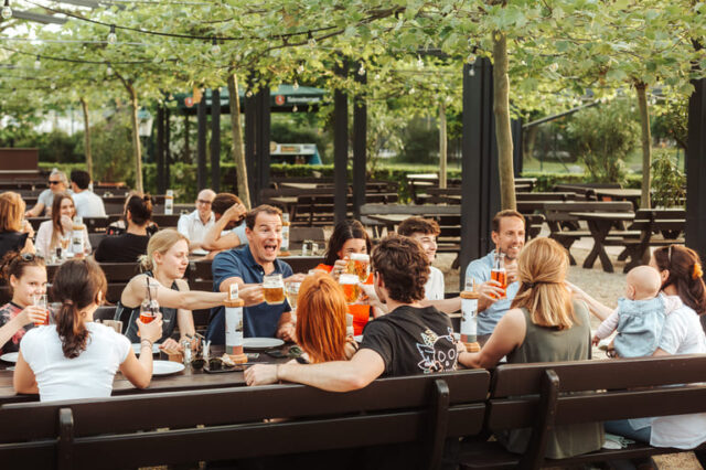 Erwachsene und Kinder sitzen im Gastgarten des Restaurants Luftburg im Prater
