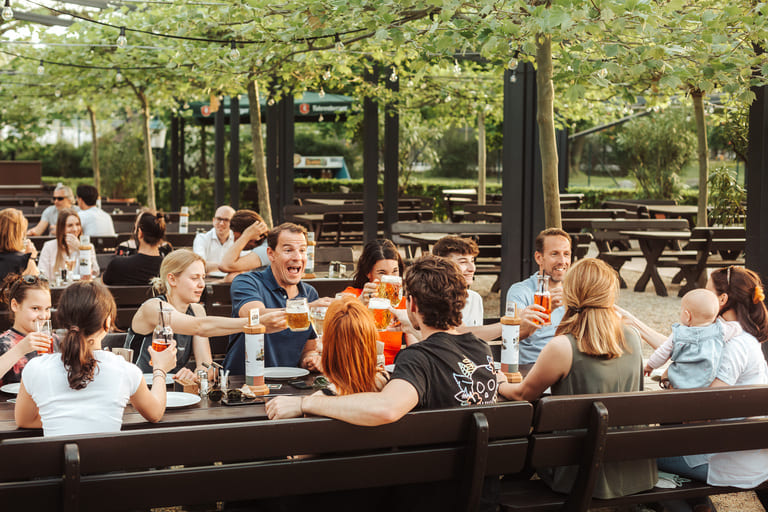Erwachsene und Kinder sitzen im Gastgarten des Restaurants Luftburg im Prater