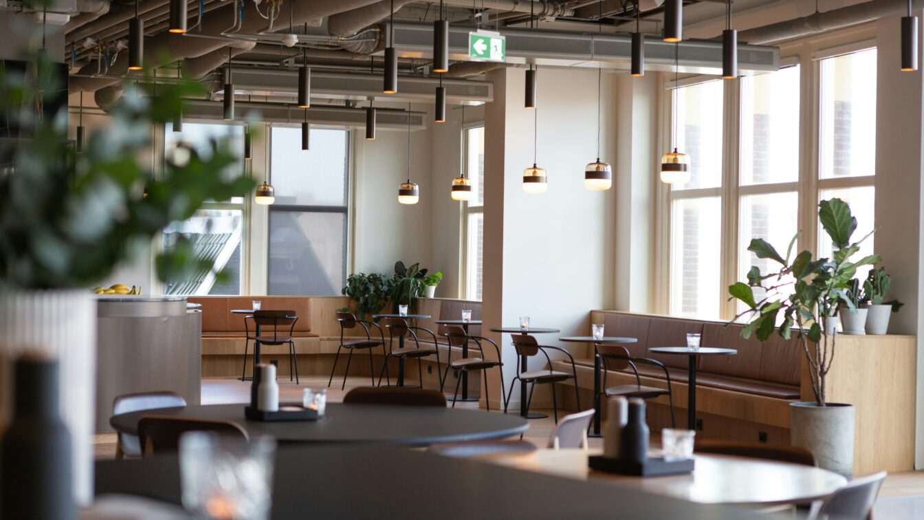 Coworking-Space mit vielen Tischen und großen Fenstern