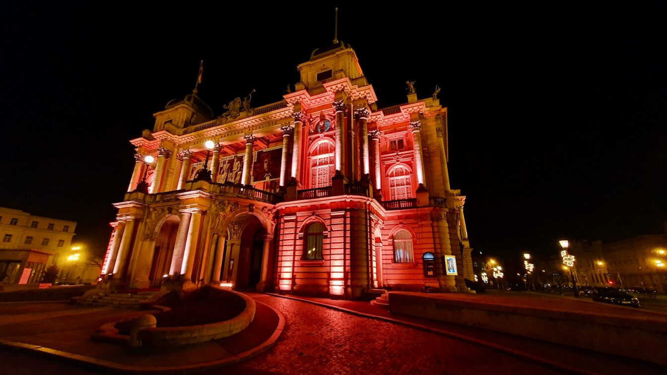 Ein großes, imposantes Gebäude, das rot beleuchtet wird bei Nacht.