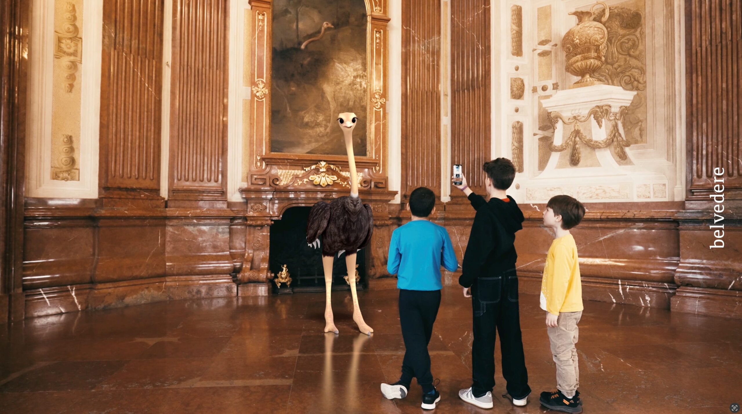 Kinder spielen ein Virtual Reality Spiel im Belvedere, vor ihnen steht ein Pfau
