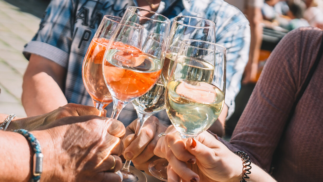mehrere Menschen stoßen mit Gläsern Wein an