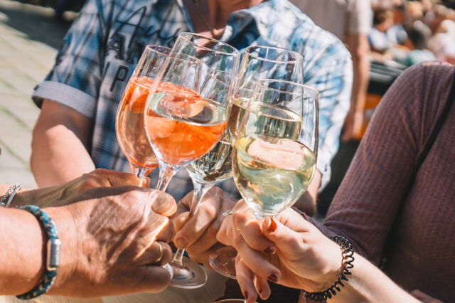mehrere Menschen stoßen mit Gläsern Wein an