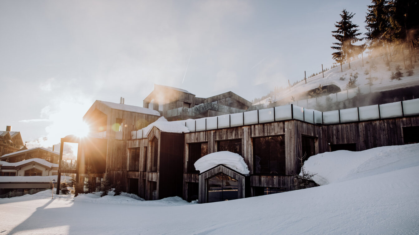 Eine schneebedeckte Landschaft, aus der sich das Naturhotel Forsthofgut erhebt.