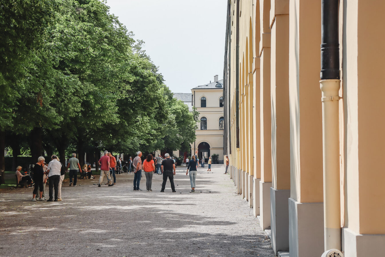 Menschen spielen Boule im Hofgarten in München – ein beliebter Treffpunkt für kostenlose Freizeitaktivitäten im Grünen. Gratis München Tipp für entspannte Stunden in historischer Kulisse.